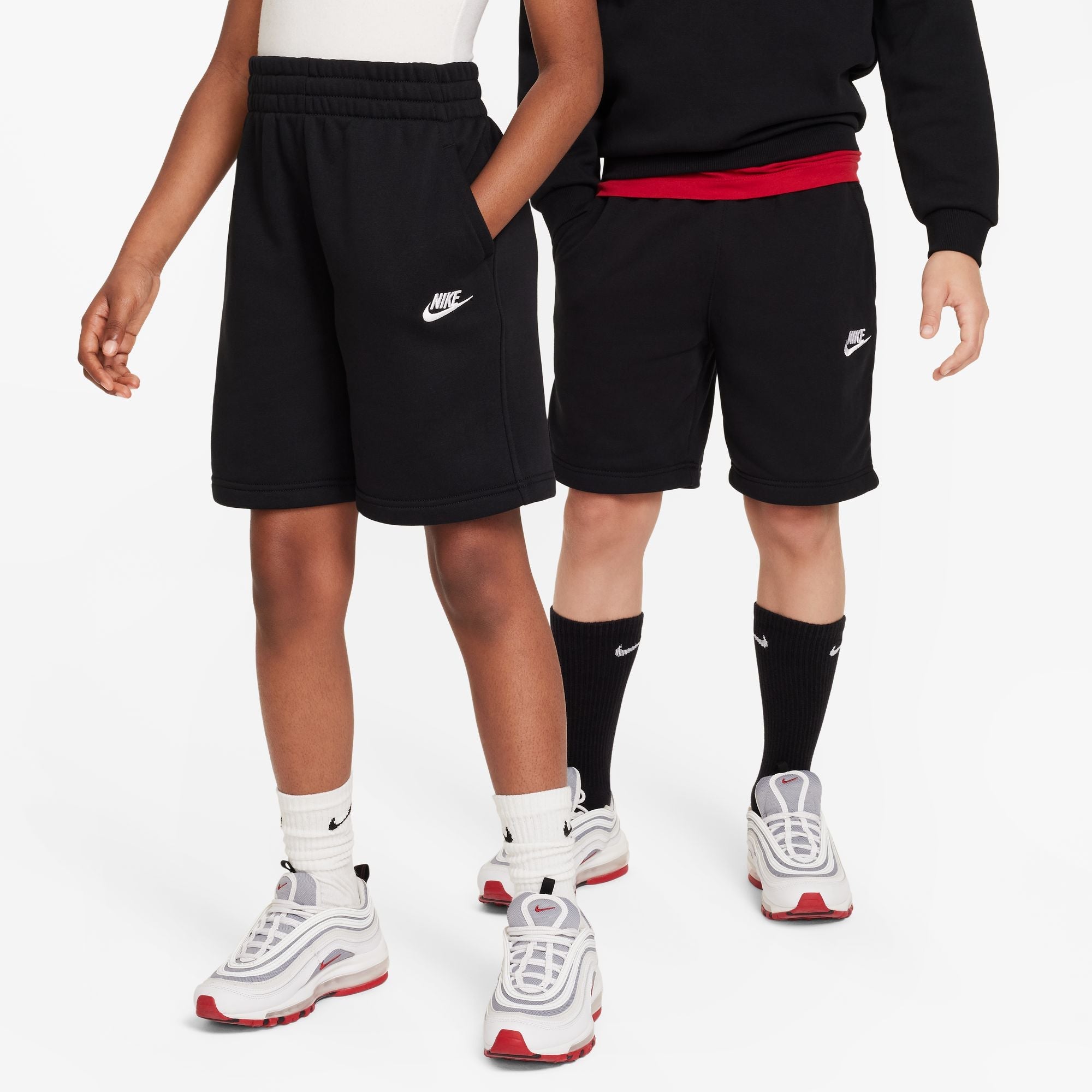 Two people wearing black Nike shorts on a white background