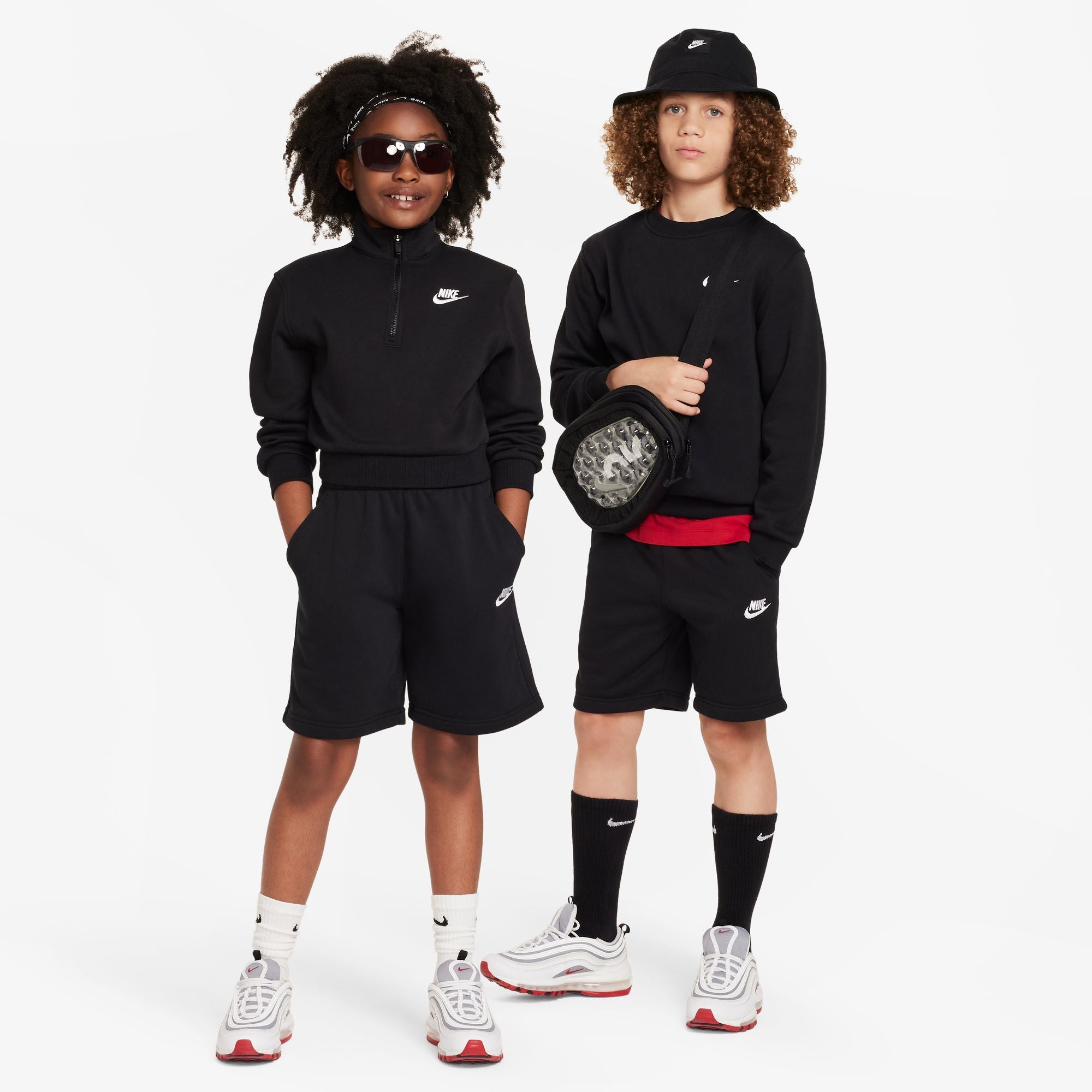 Two children wearing matching black outfits with Nike logos on a white background
