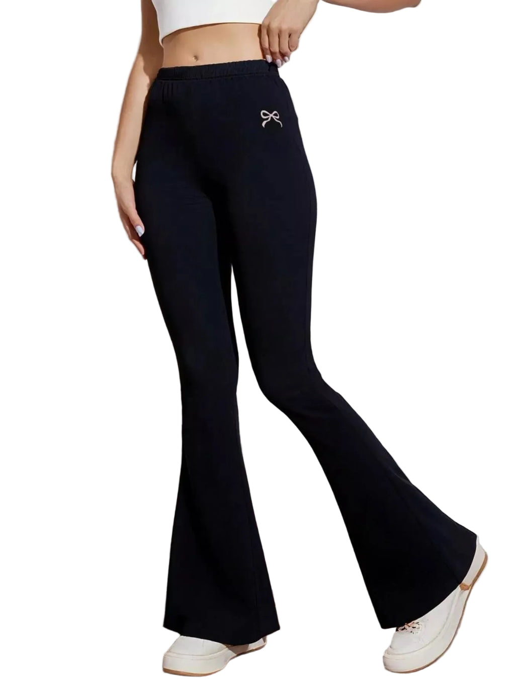 Person wearing black flared pants with a white bow detail in a minimalistic setting.