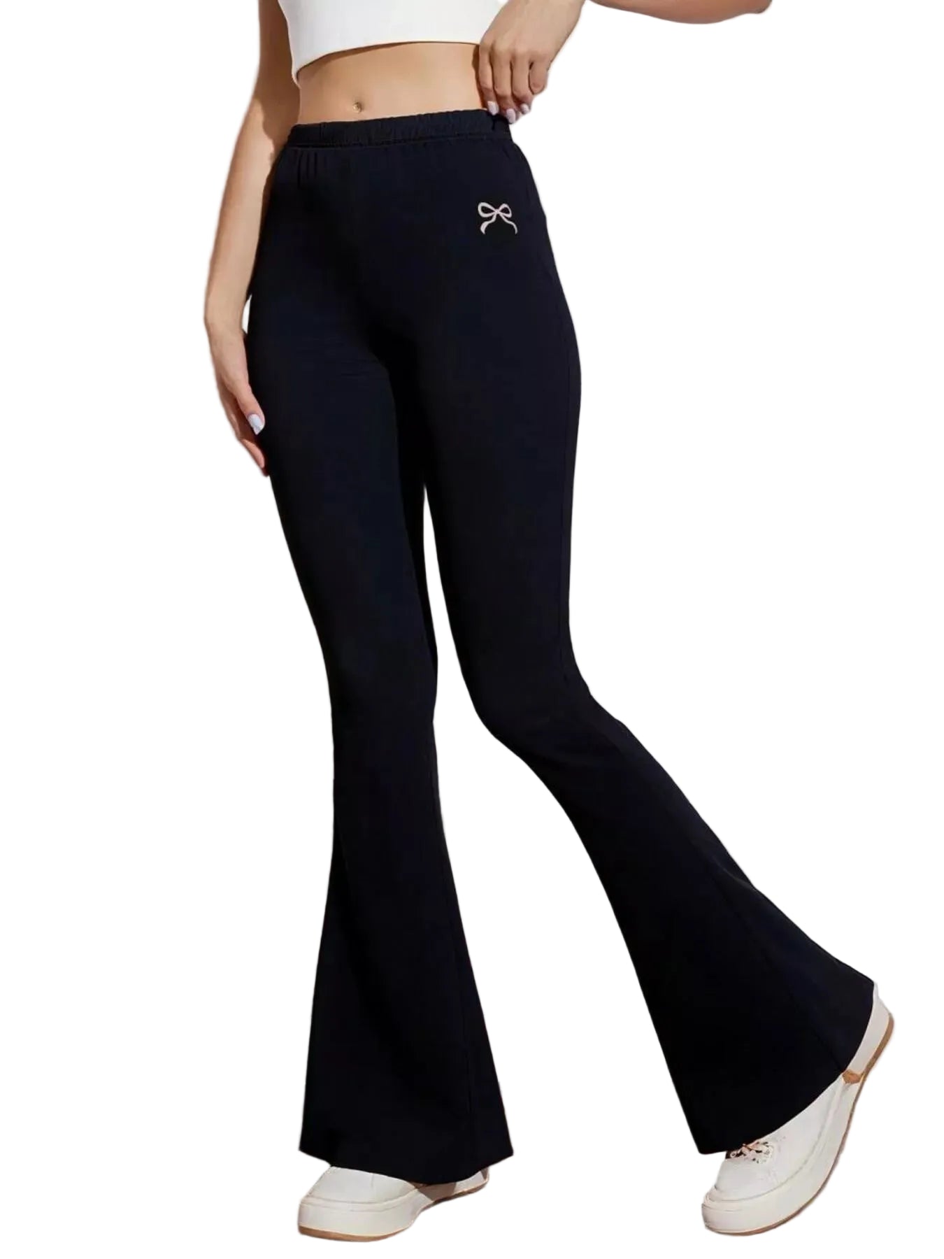 Person wearing black flared pants with a white bow detail in a minimalistic setting.