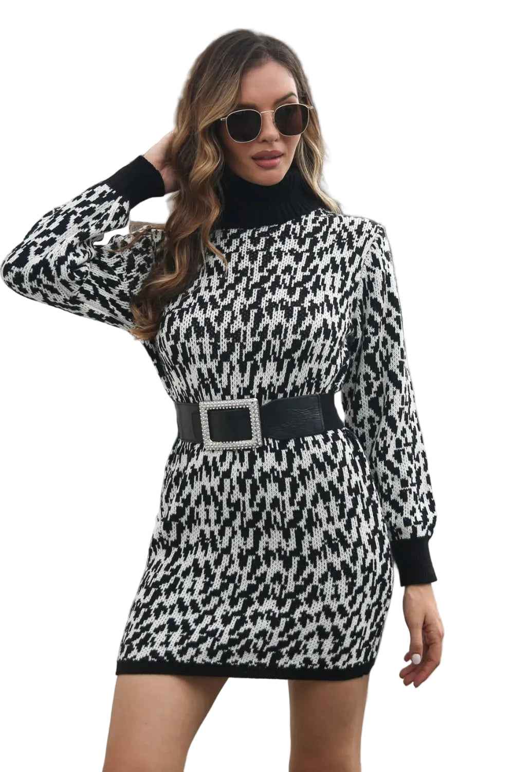 Woman wearing a black and white patterned dress with a belt, standing against a building.