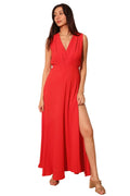 Woman wearing a red dress with a slit standing against a plain background