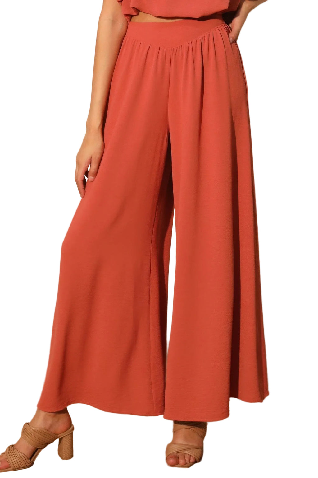 Person wearing coral-colored wide-leg pants against a neutral background