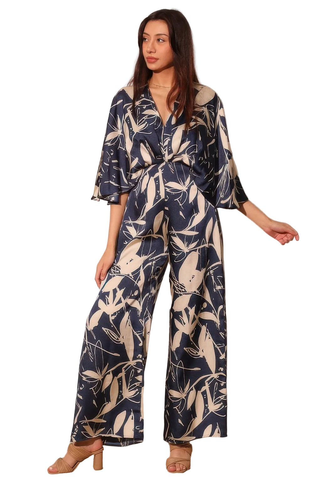 Woman wearing a navy blue and white floral jumpsuit against a plain background