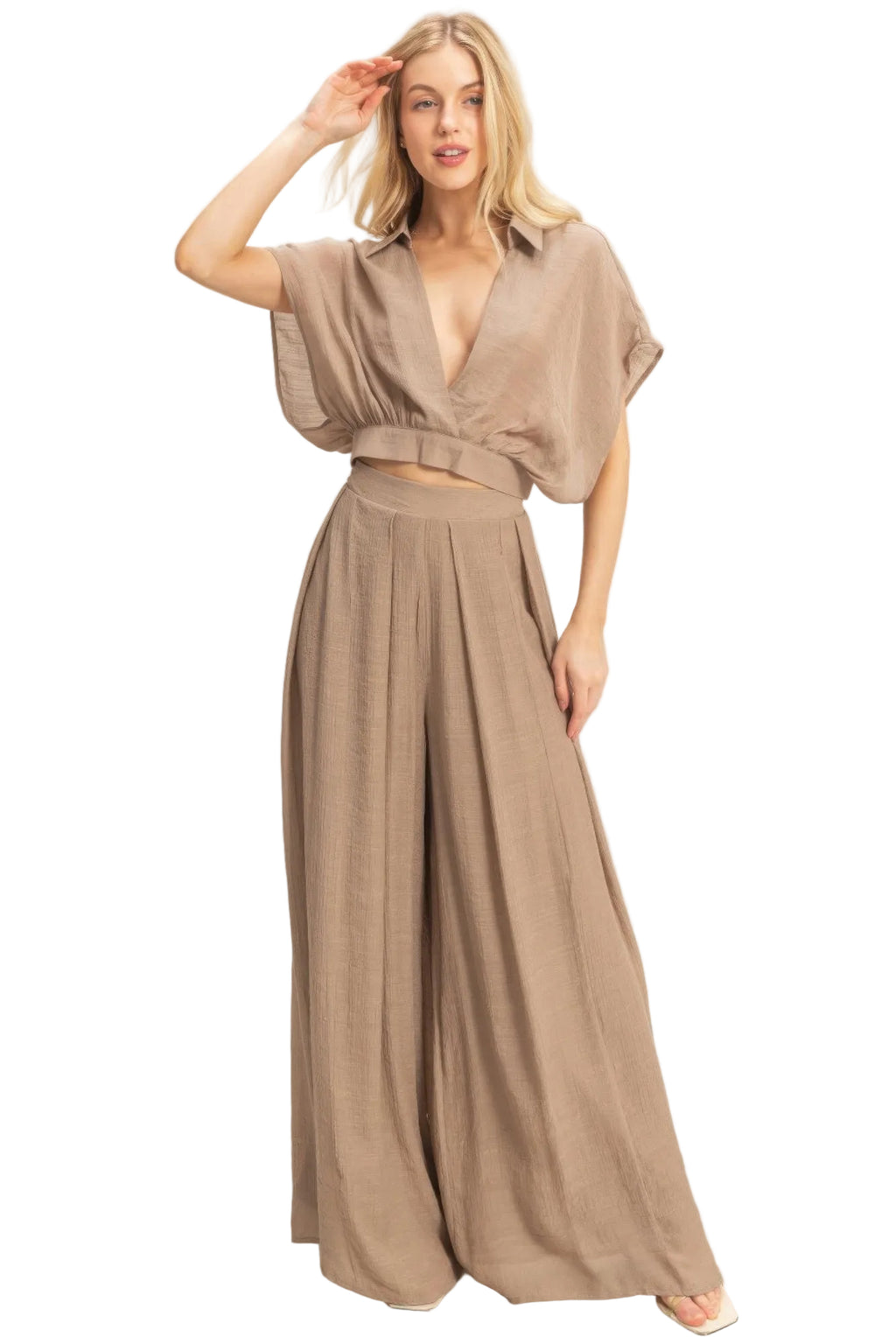 Woman wearing a beige wide leg pant on a plain background