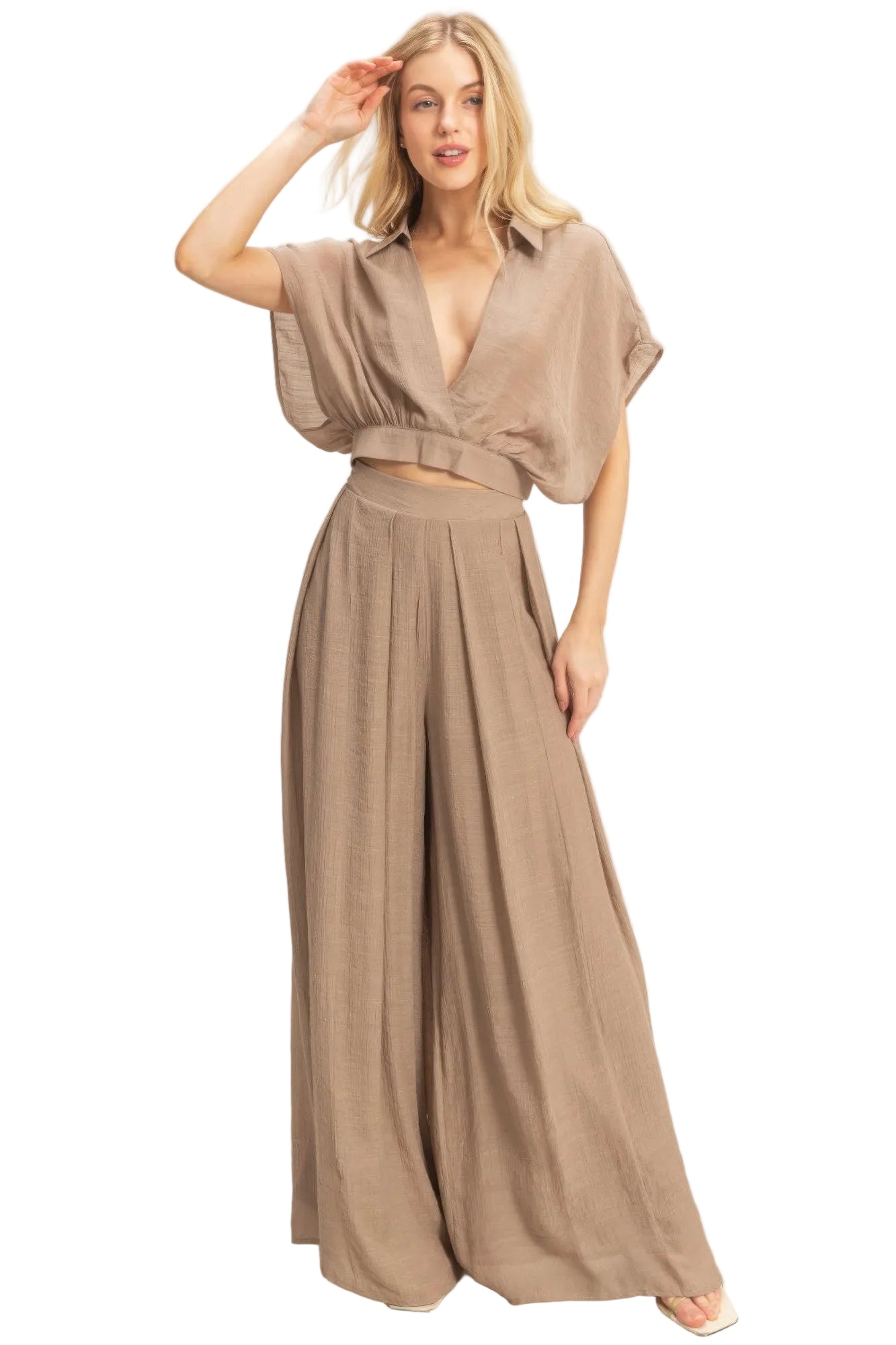 Woman wearing a beige wide leg pant on a plain background