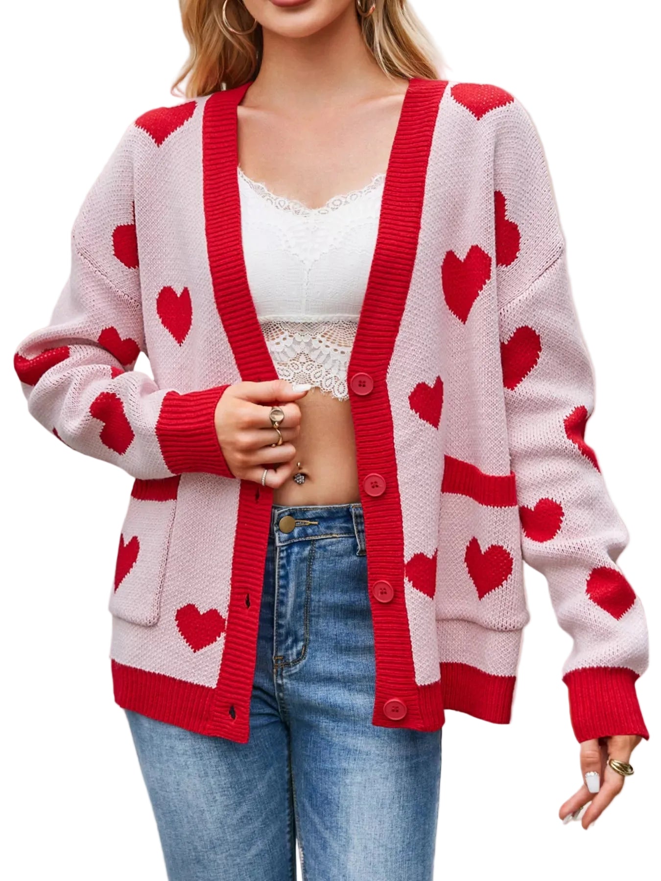 Person wearing a white cardigan with red heart patterns, a white top, and blue jeans on a beige background.