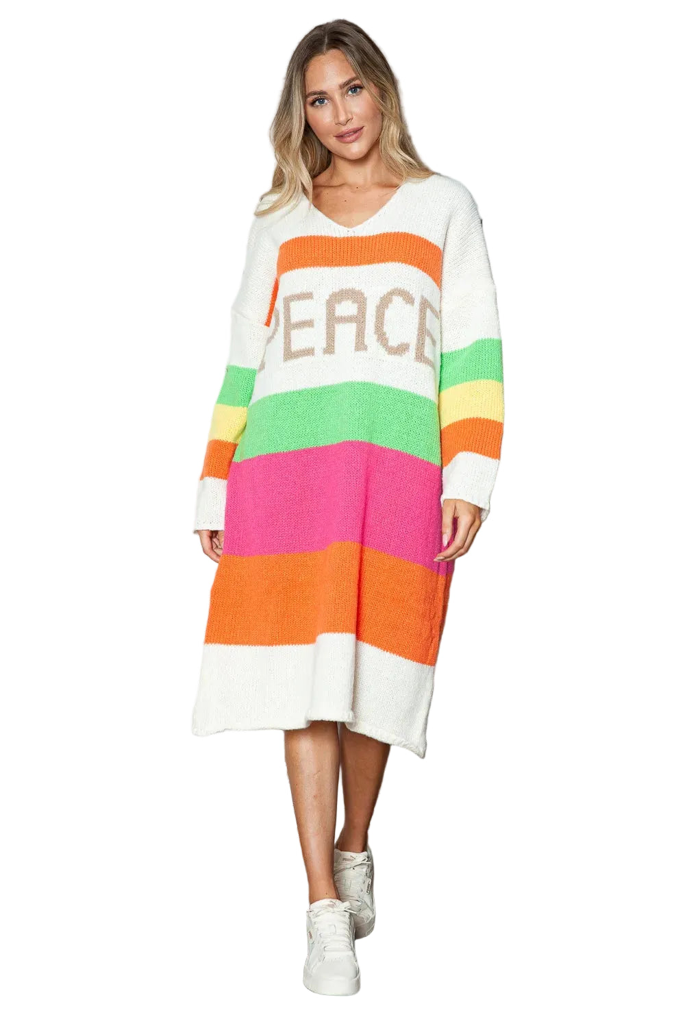 Woman wearing a colorful striped dress with 'PEACE' text, standing against a wooden wall.