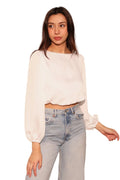 Woman wearing a white blouse and light blue jeans against a plain background