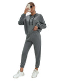 Person wearing a gray tracksuit in a minimalistic room.