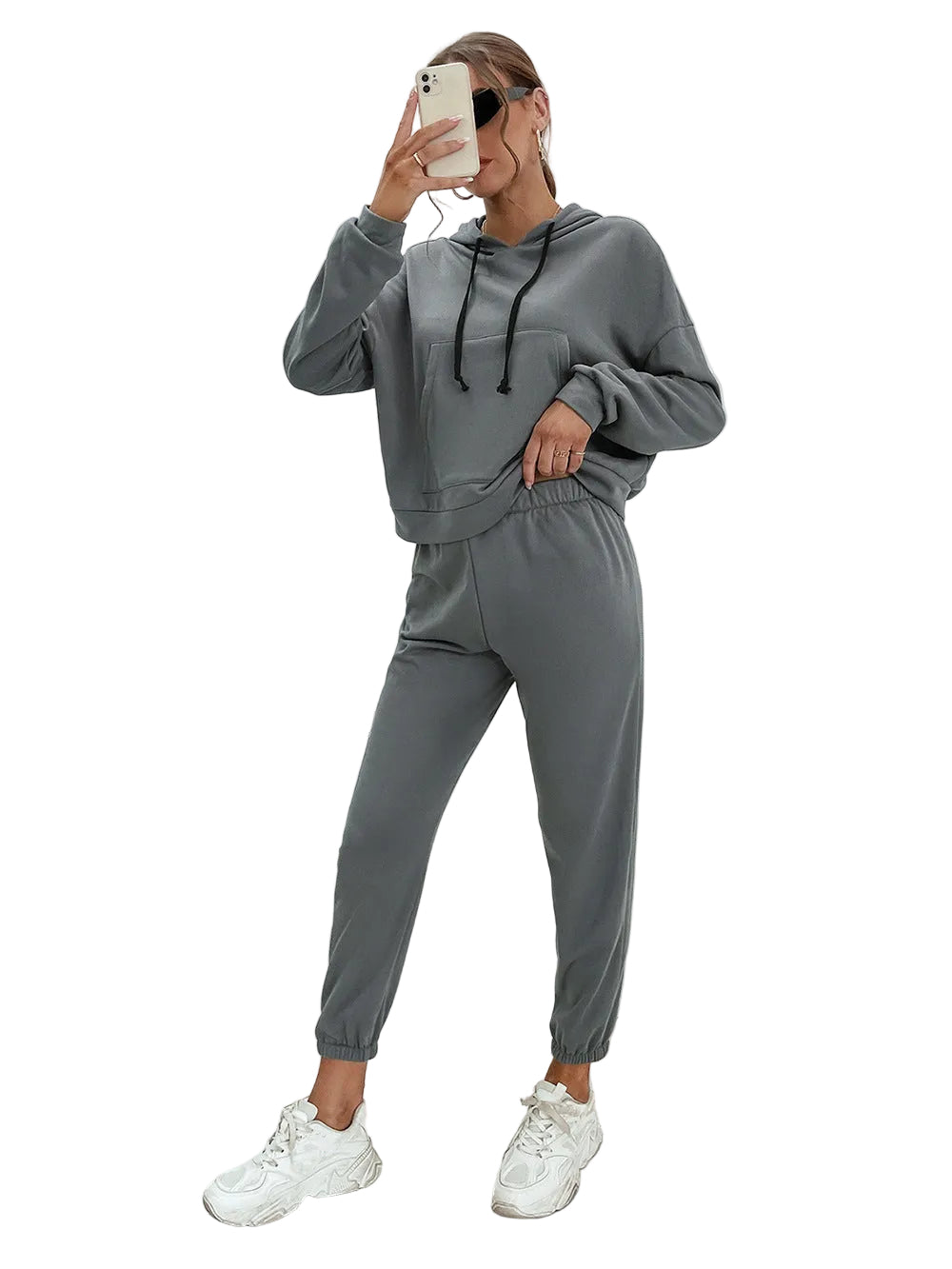Person wearing a gray tracksuit in a minimalistic room.