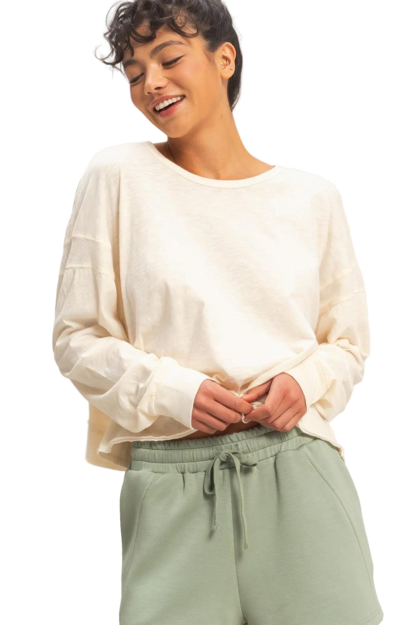 Person wearing a white long-sleeve top and light green pants against a plain background