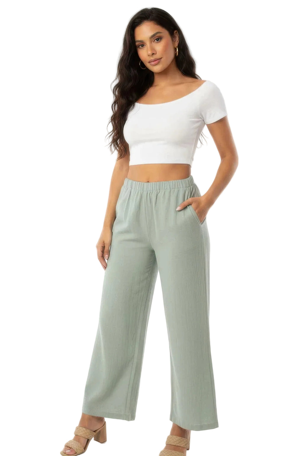 Woman wearing a white crop top and light green wide-leg pants on a white background