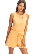 Woman wearing a yellow sleeveless top and shorts set on a plain background