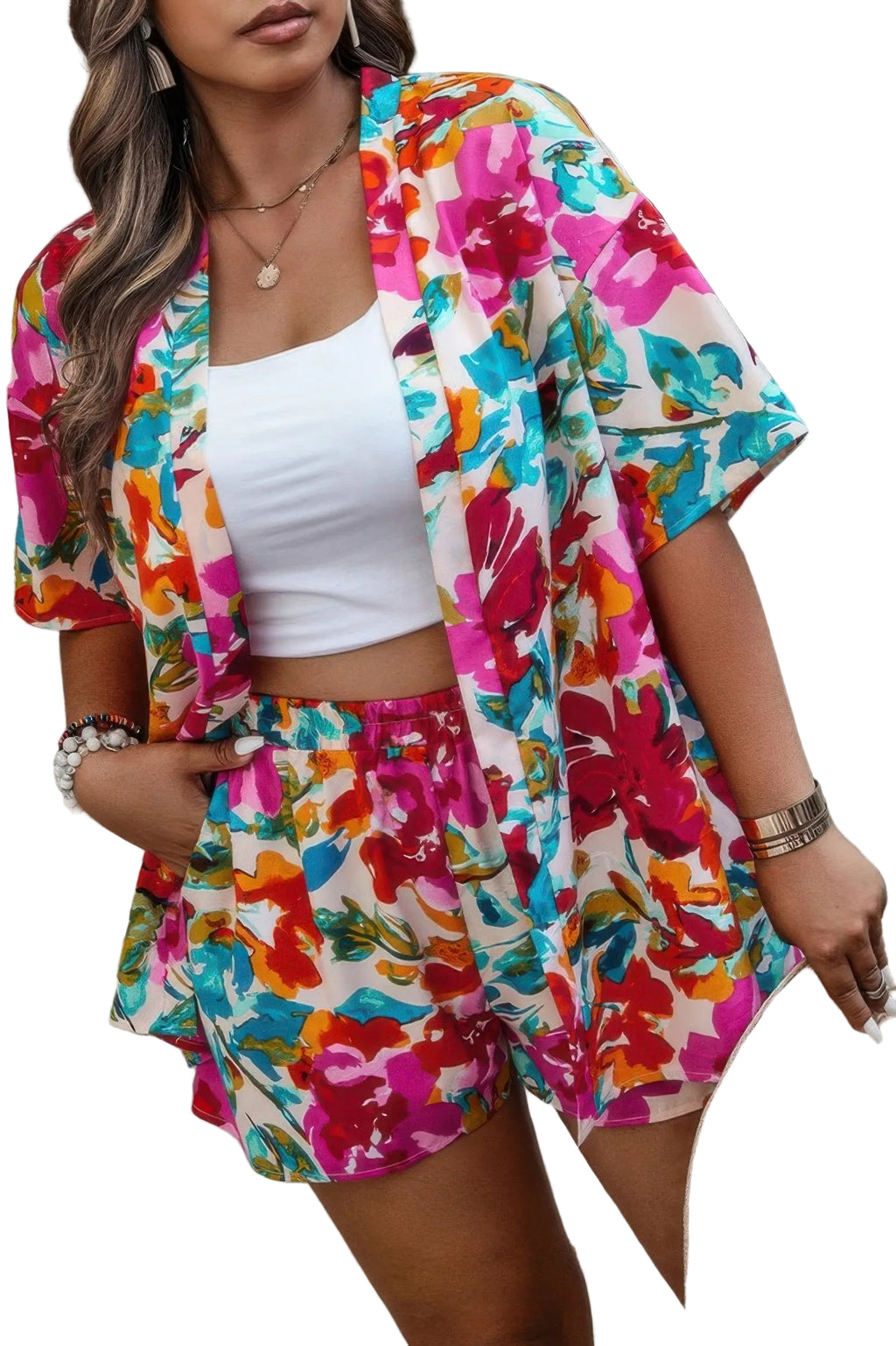 Woman wearing a colorful floral outfit with a white top and shorts, standing against a green curtain.