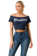 Woman wearing a navy blue 'Brooklyn' crop top and blue jeans on a beige background