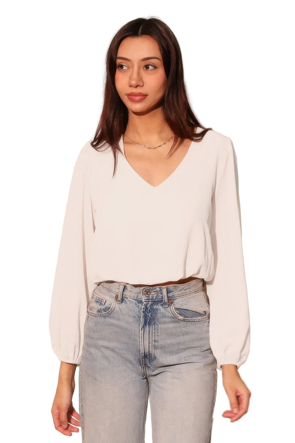 Woman wearing a white blouse and light blue jeans against a plain background