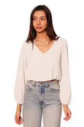 Woman wearing a white blouse and light blue jeans against a plain background