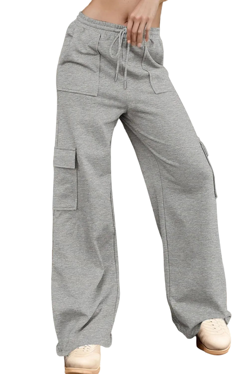 Person wearing gray cargo pants standing against a wooden wall.