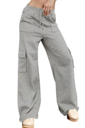 Person wearing gray cargo pants standing against a wooden wall.
