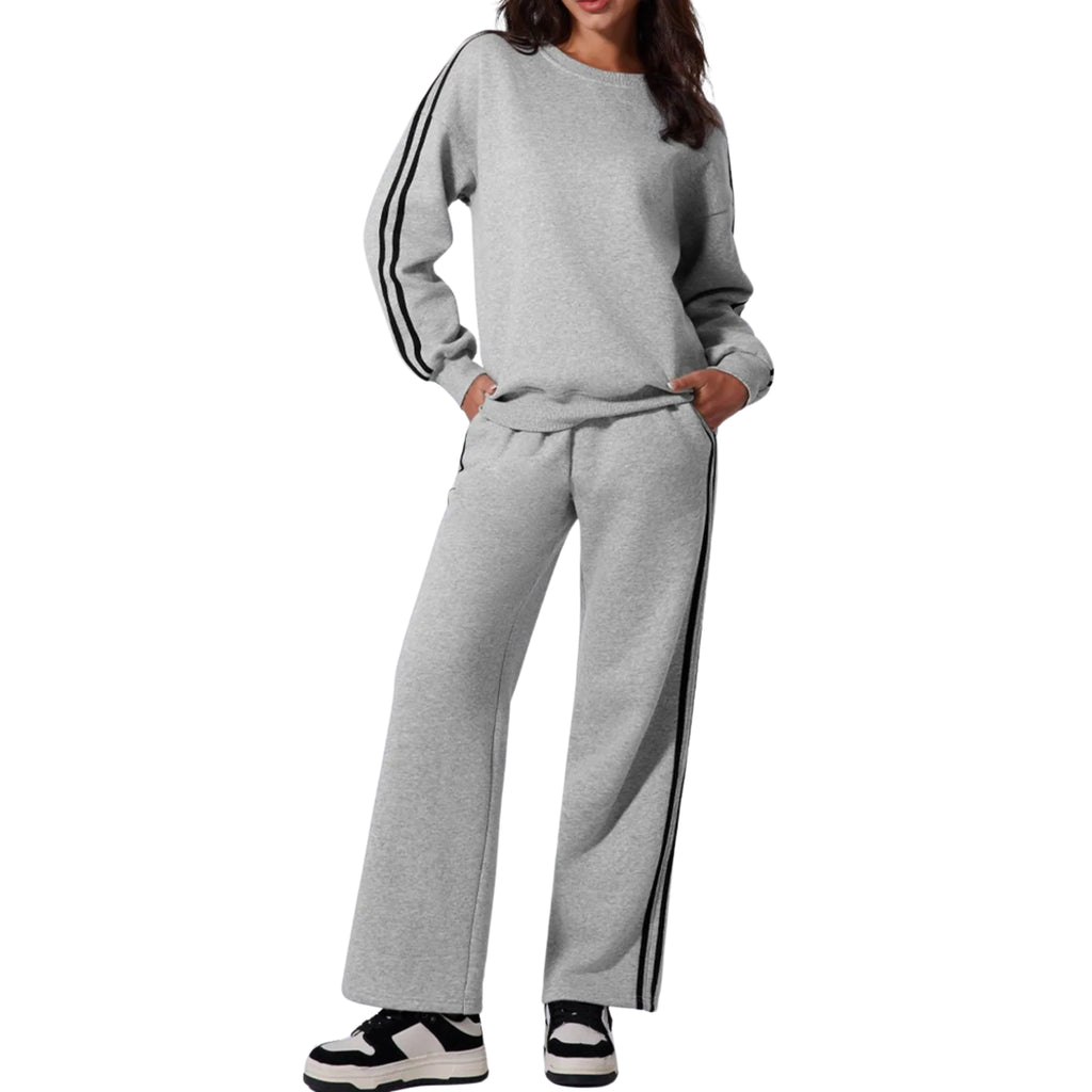 A woman wearing a grey side striped round neck top and matching high-waisted pants with side stripes, standing against a white background.