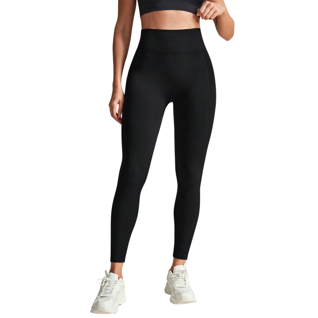 A woman wearing high-waisted black performance leggings and white sneakers.