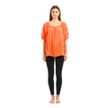 Woman wearing an orange top and black leggings on a white background