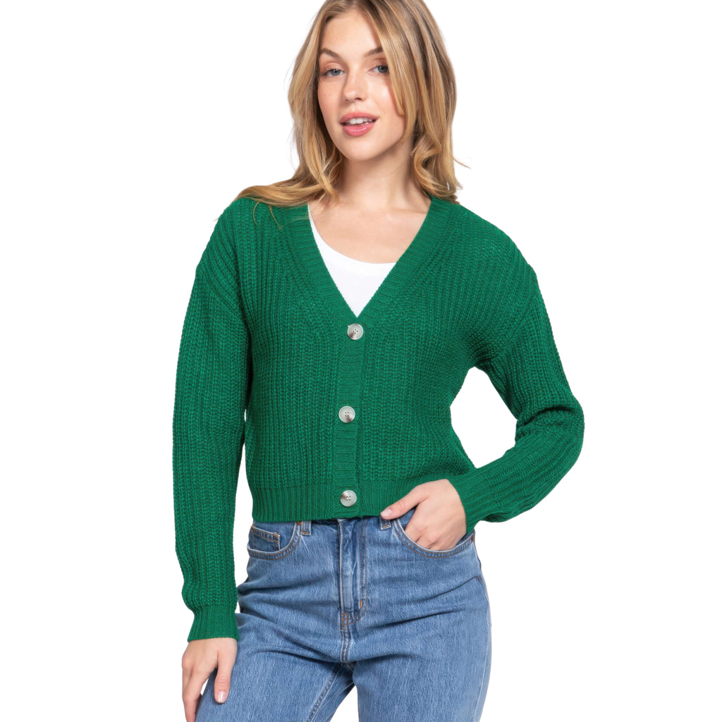 Woman wearing a green cardigan over a white shirt and blue jeans on a white background