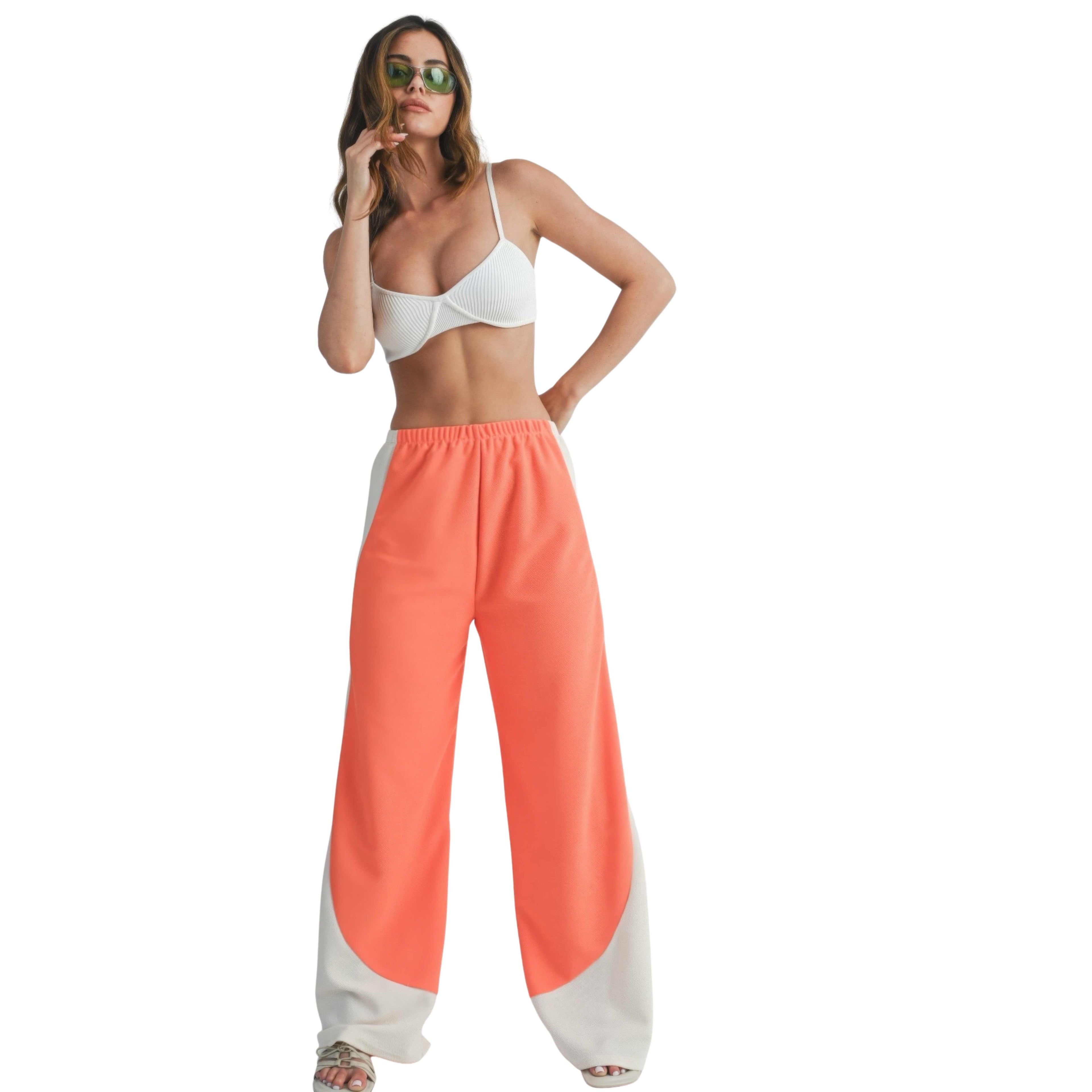 Woman wearing a white bikini top and wide leg pants on a white background