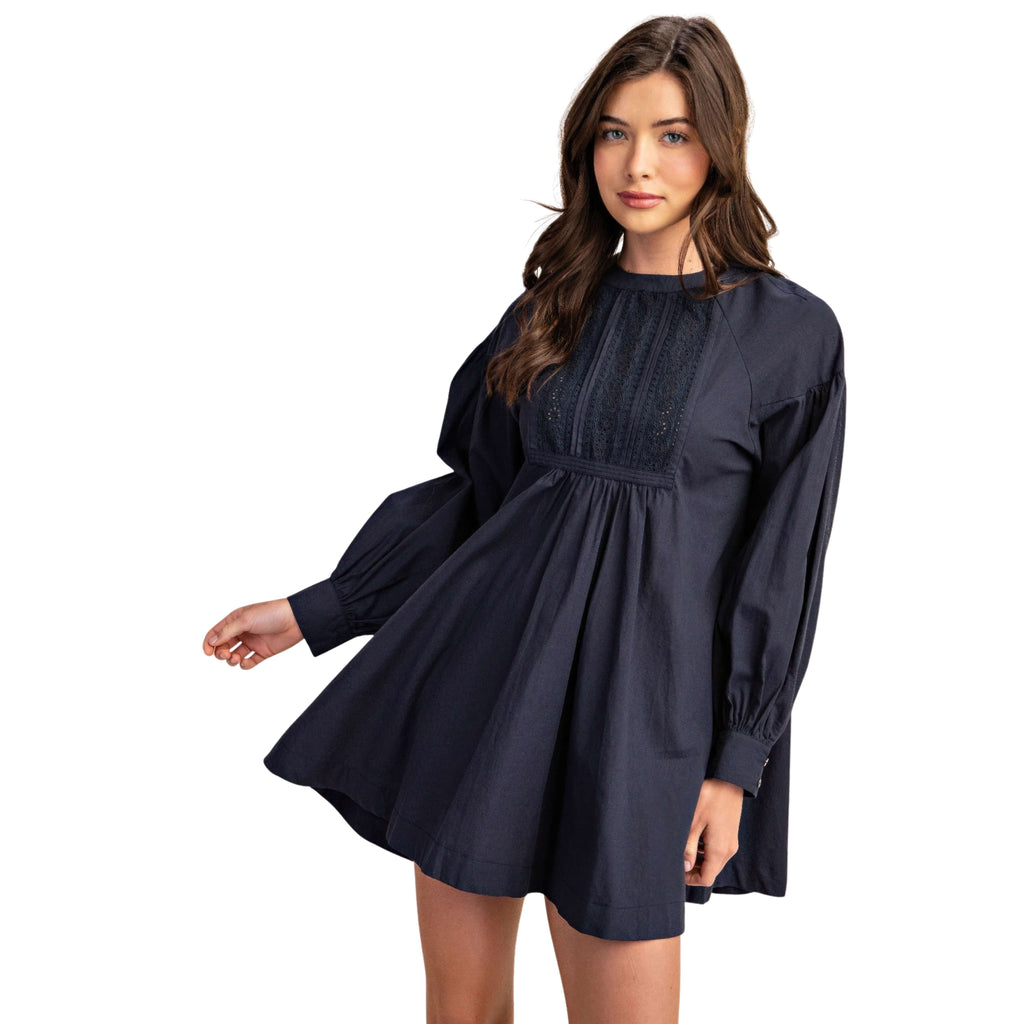 Woman wearing a navy blue dress with long sleeves on a white background