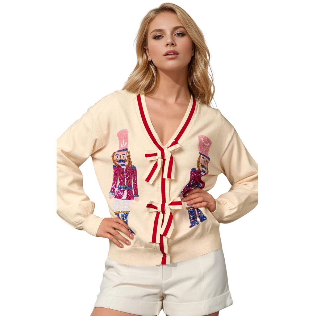 Woman wearing a cream cardigan with Nutcracker design on a white background