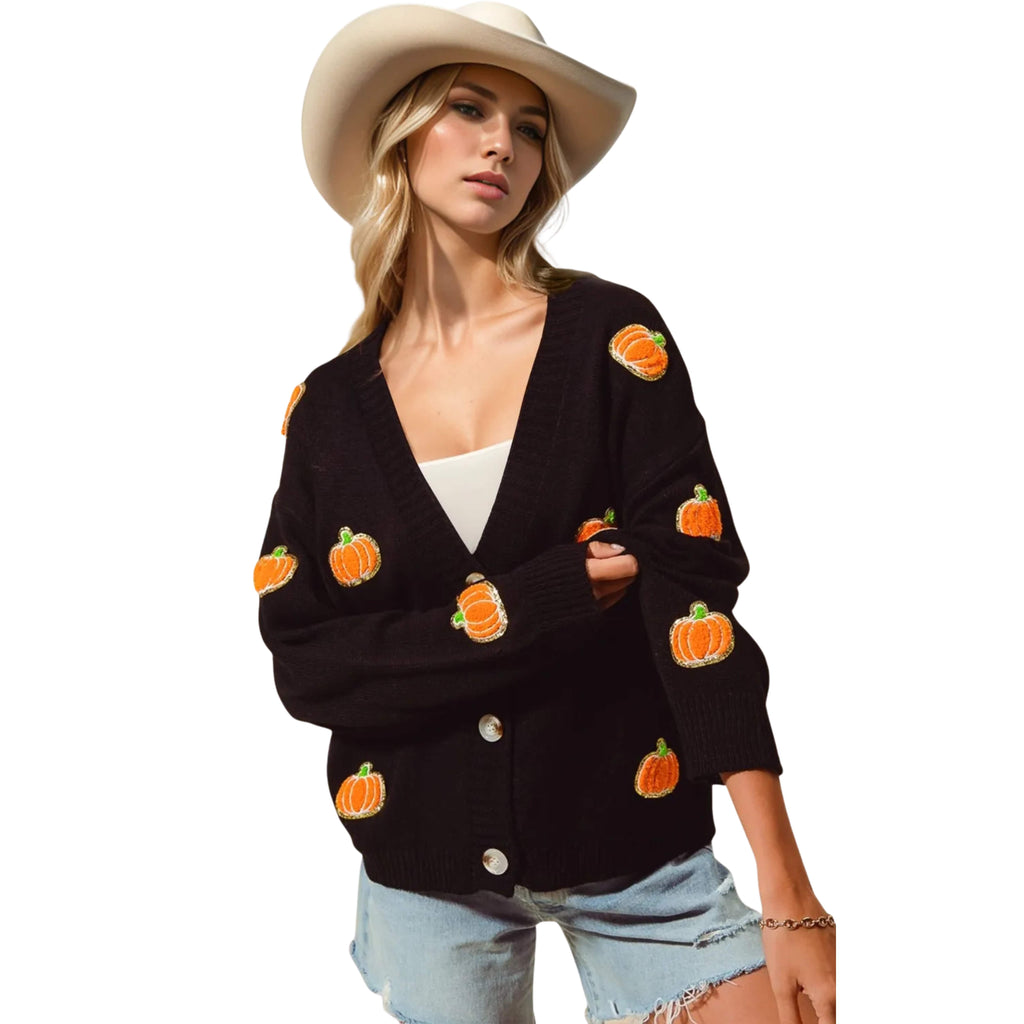 Woman wearing a black cardigan with pumpkin patterns on a white background