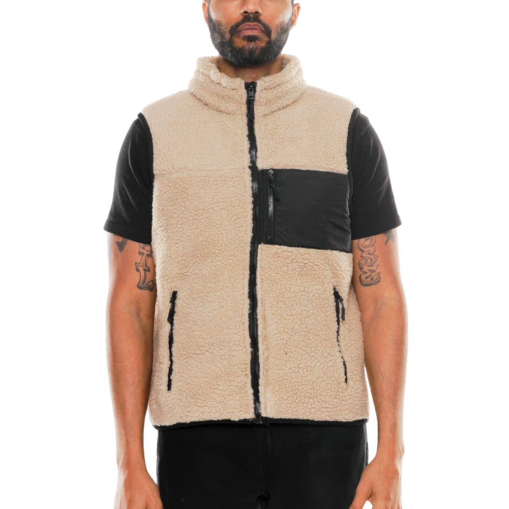 Man wearing a beige fleece vest with black accents on a white background