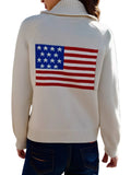 Person wearing a sweater with an American flag on the back, standing in front of a building.