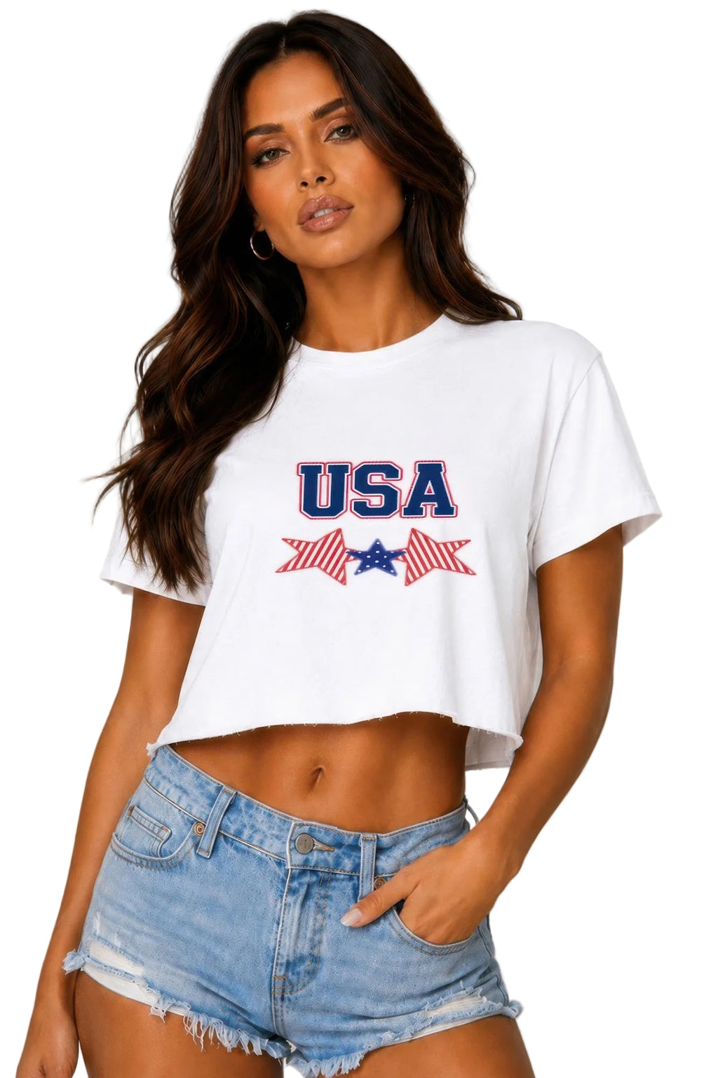 A woman modeling a white cropped t-shirt with a red, white, and blue 'USA' graphic on the chest, paired with light-wash denim shorts, against a neutral gray studio background.