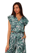 Woman wearing a green and white patterned outfit against a plain background