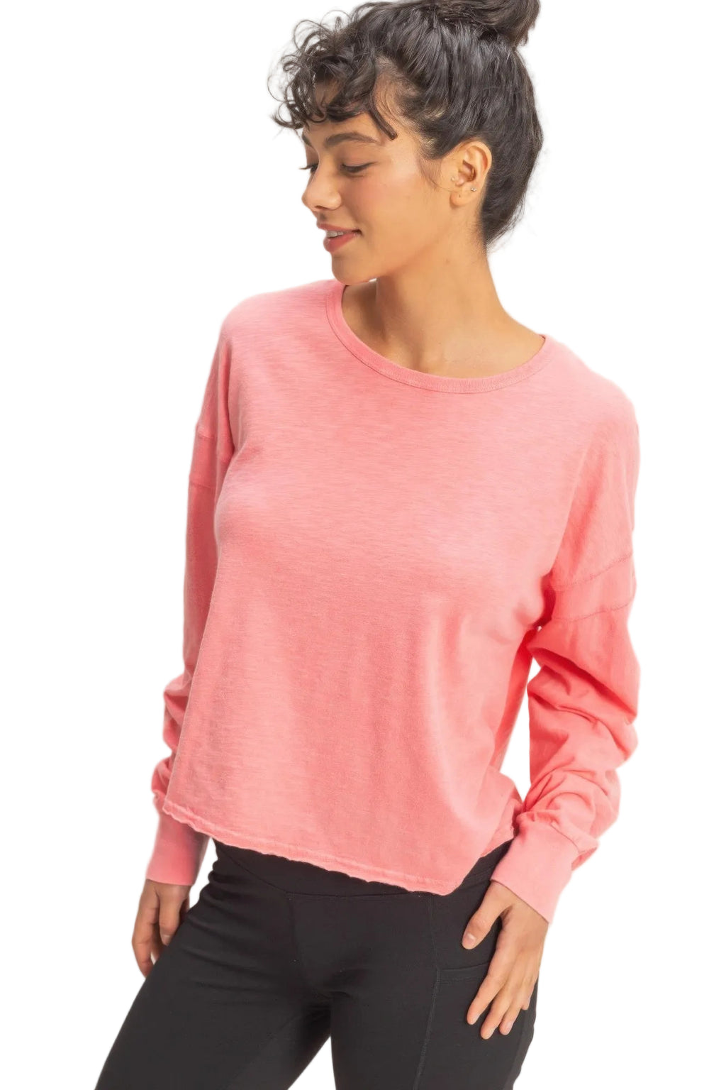 Woman wearing a pink long-sleeve top against a beige background