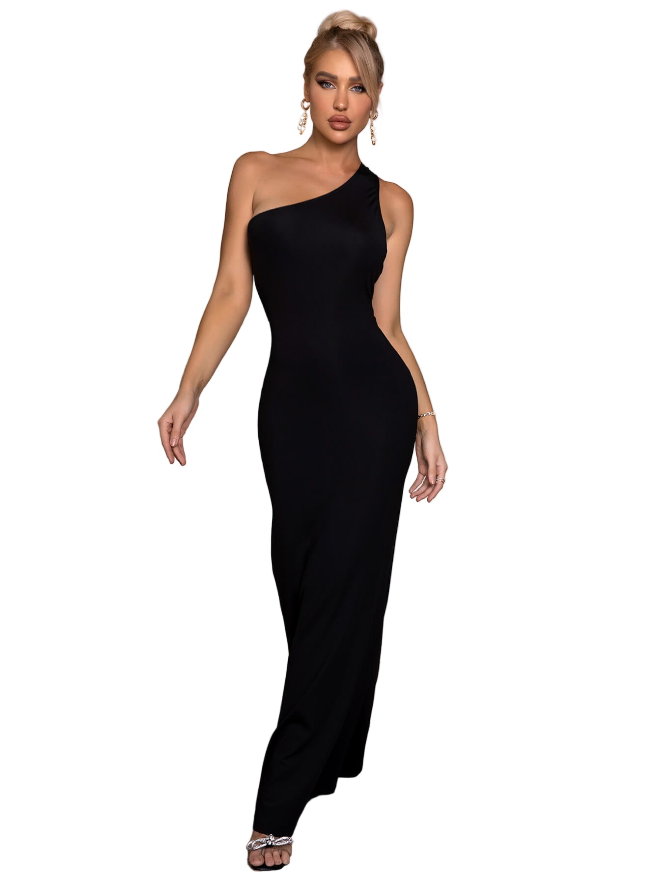 Woman in a black one-shoulder dress standing in a bedroom.