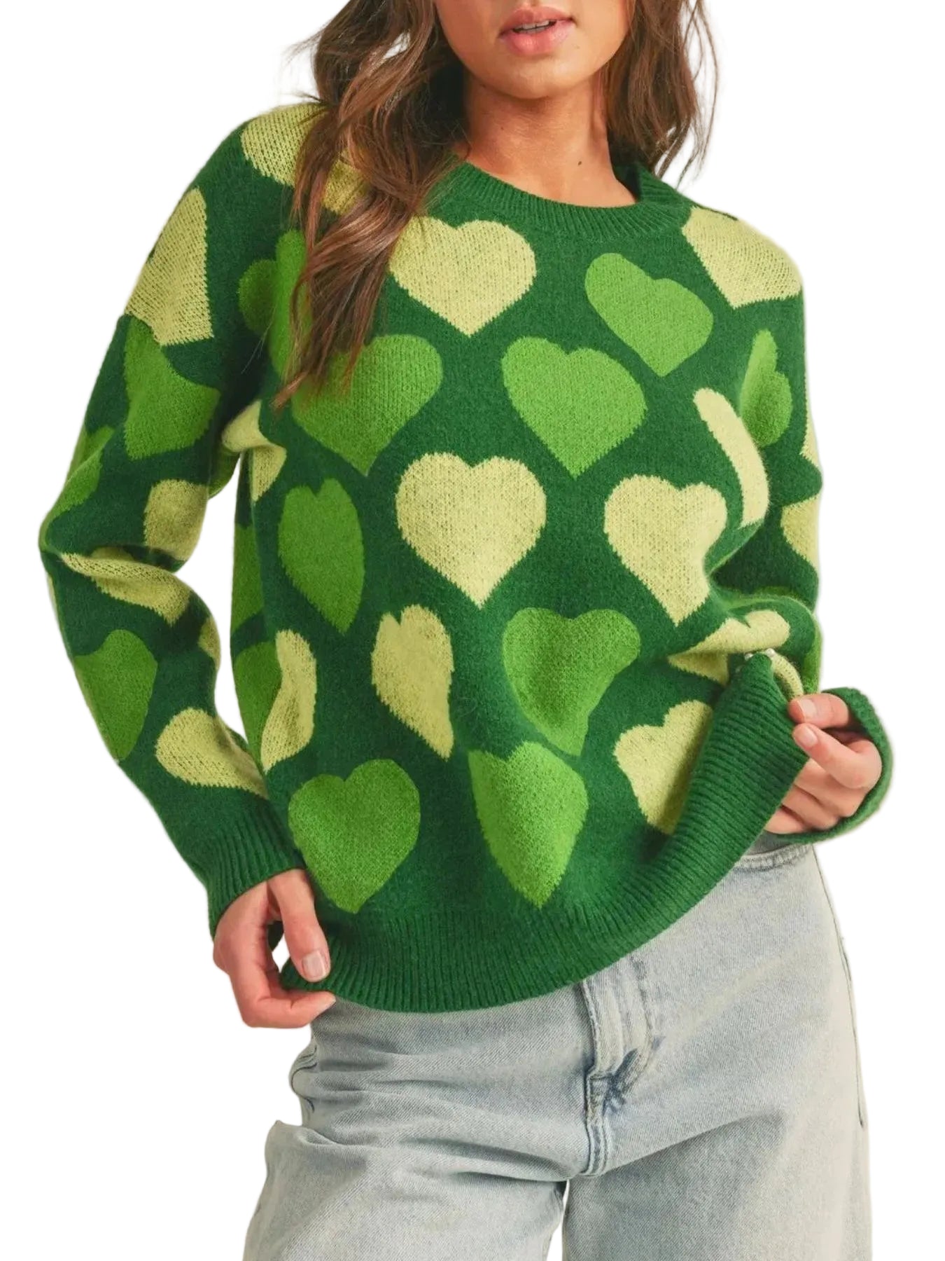 Person wearing a green sweater with heart patterns on a beige background