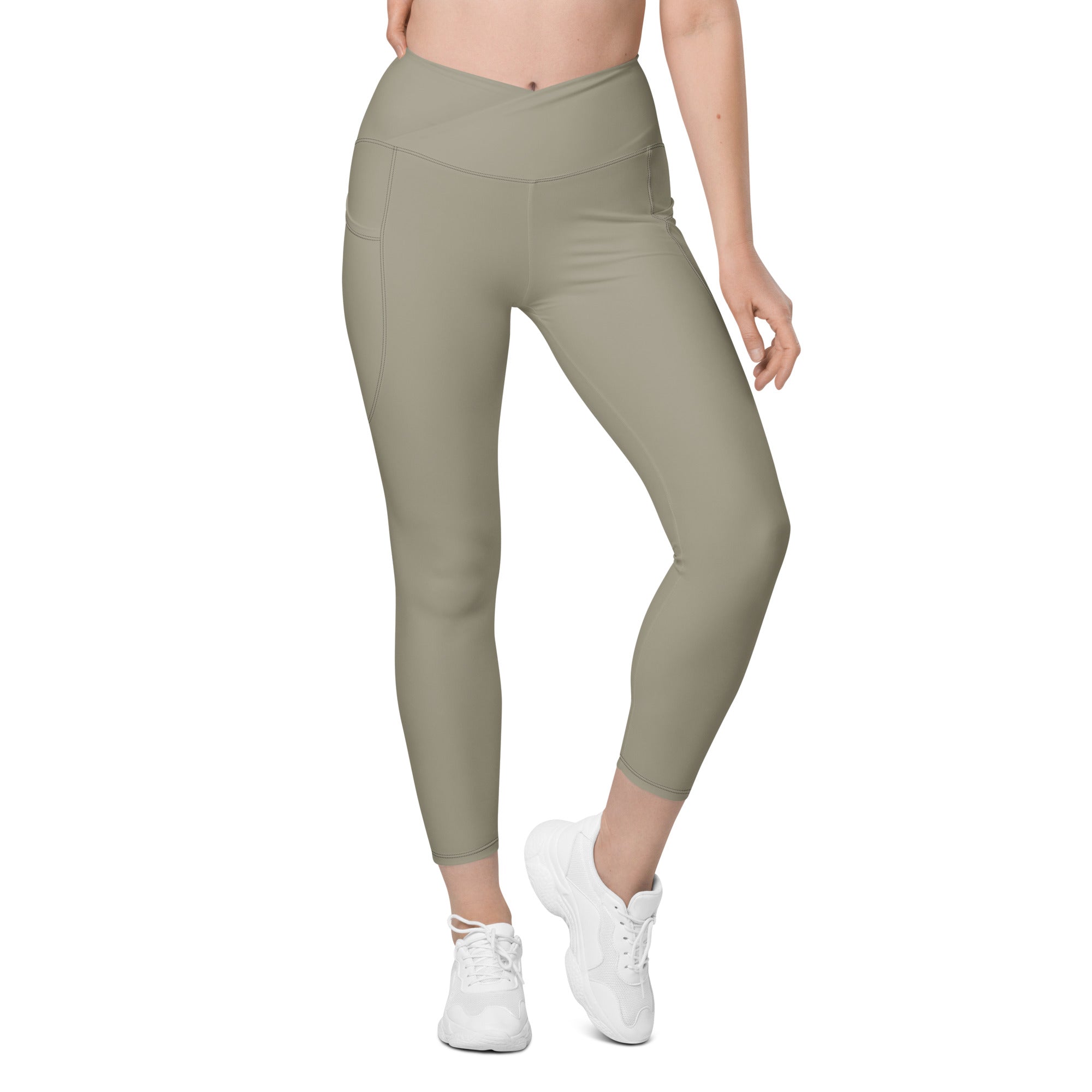 A pair of high-waisted, crossover design women's leggings in green, featuring pockets on the sides and a soft, stretchy fabric.