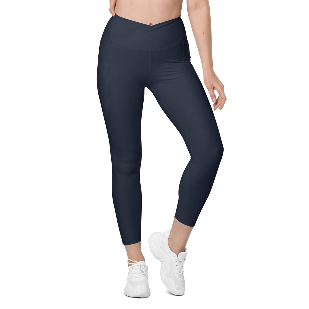 A model wearing high-waisted women's pocket leggings in navy color, featuring a crossover design and pockets on the sides.