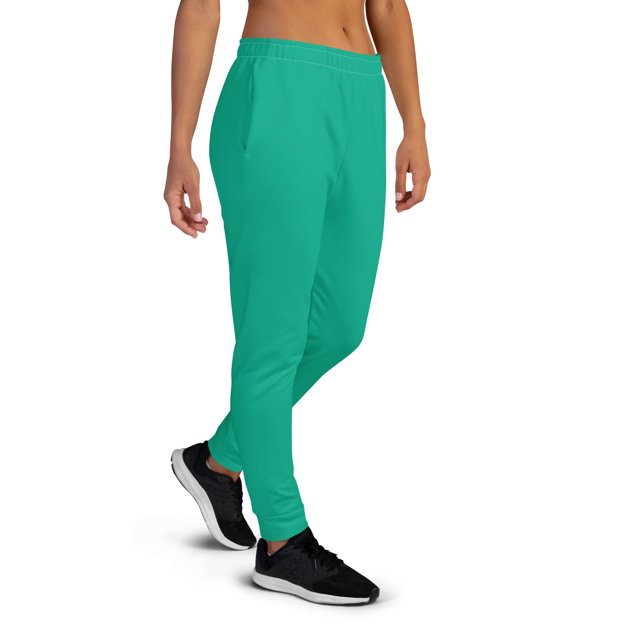 A woman wearing green full-length joggers and black shoes, standing against a white background.