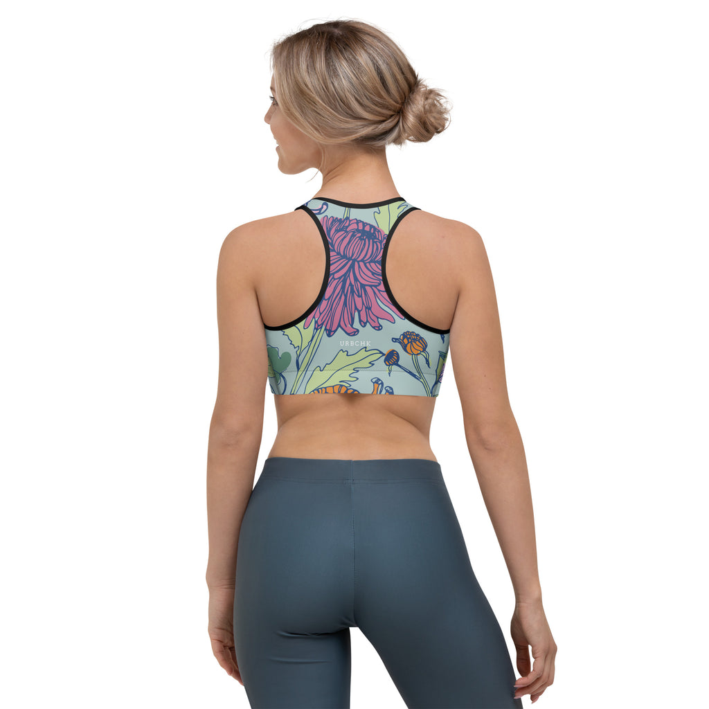 A woman wearing a sports bra with a multicolored floral design in the front and solid blue sports leggings.