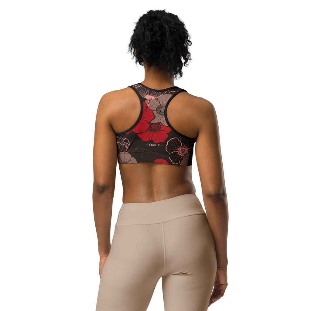 A sports bra with a floral pattern in shades of red and white, viewed from the back.