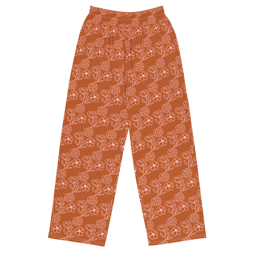A pair of orange wide-leg pants with a floral pattern, featuring an elastic waistband with a white drawstring and practical side pockets.