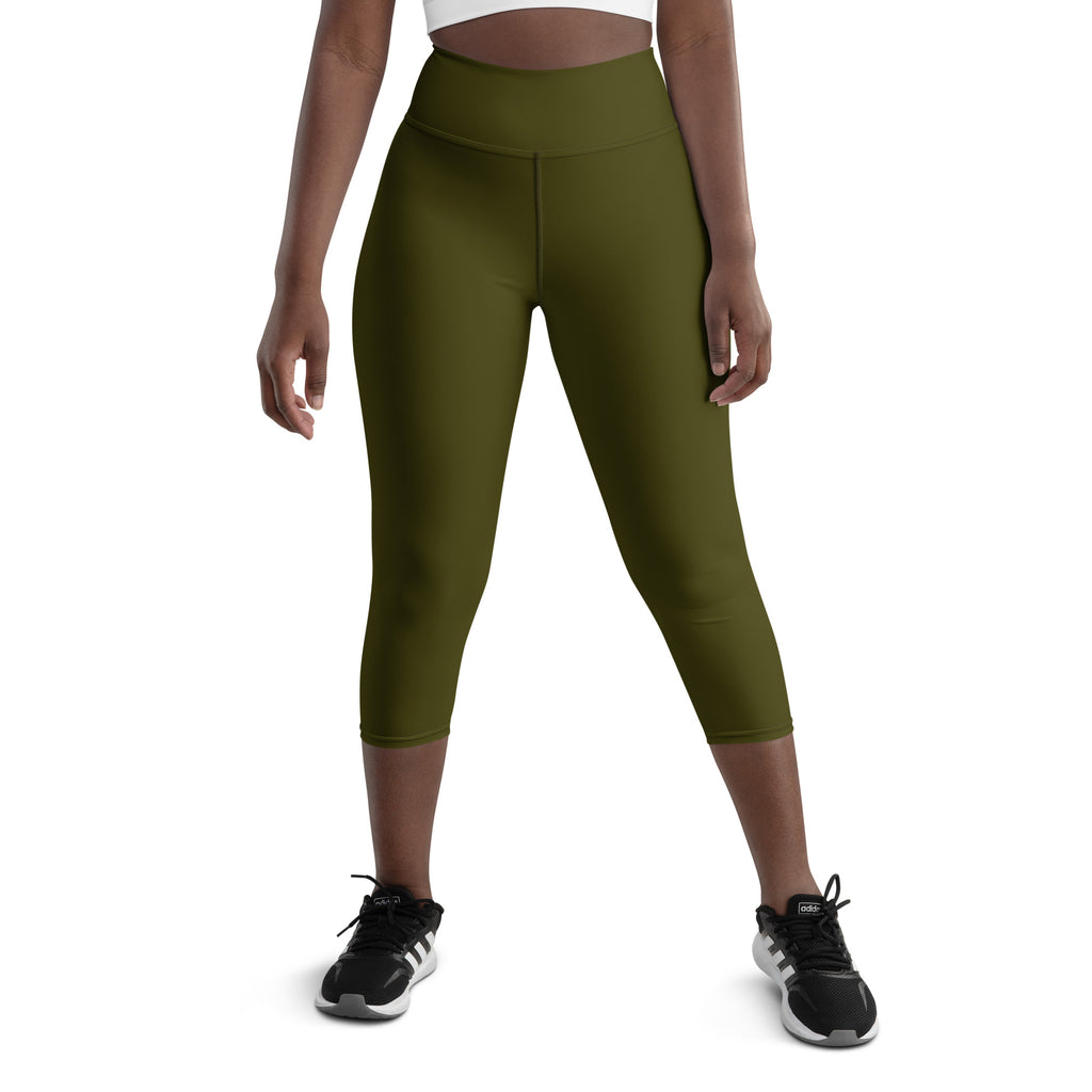A person wearing high-waisted green capri leggings with an exercise band around the thigh. The person is standing sideways and facing forward, showing the front view of the leggings.
