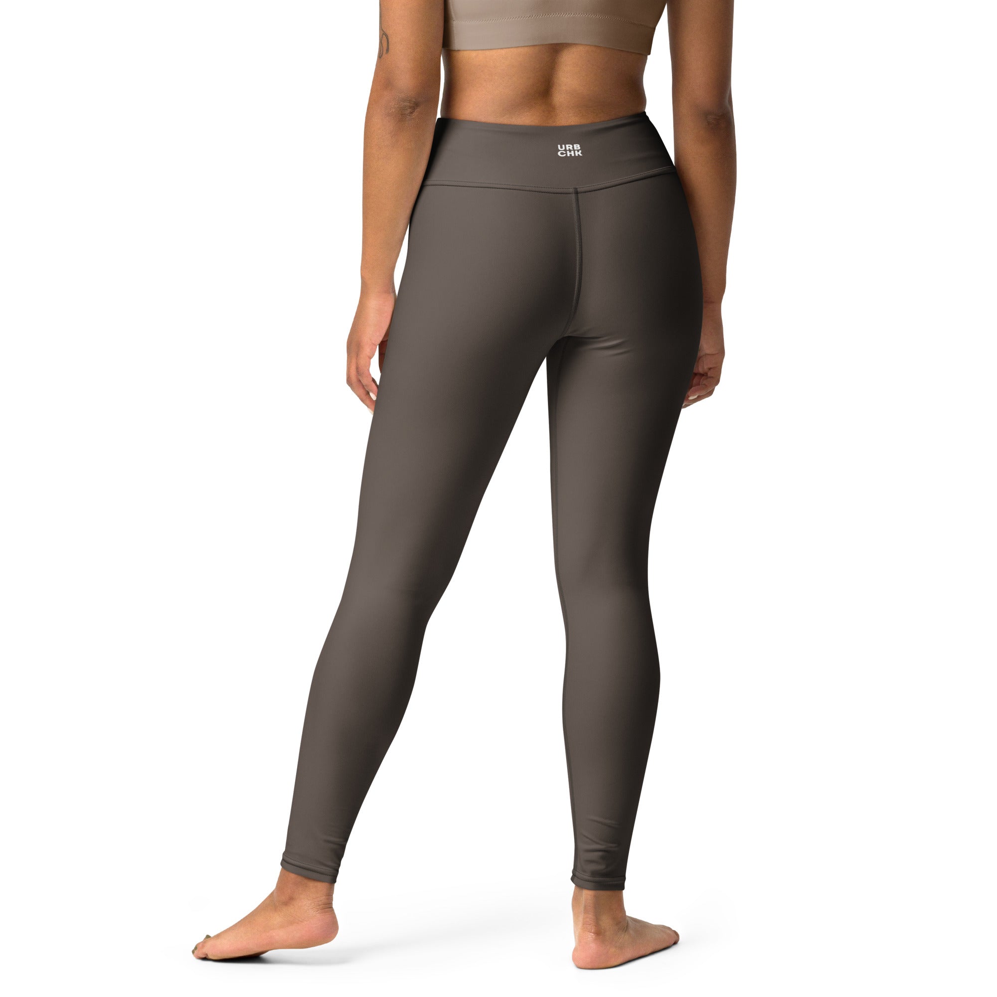 A woman standing wearing high-waisted yoga leggings and a white sports top.