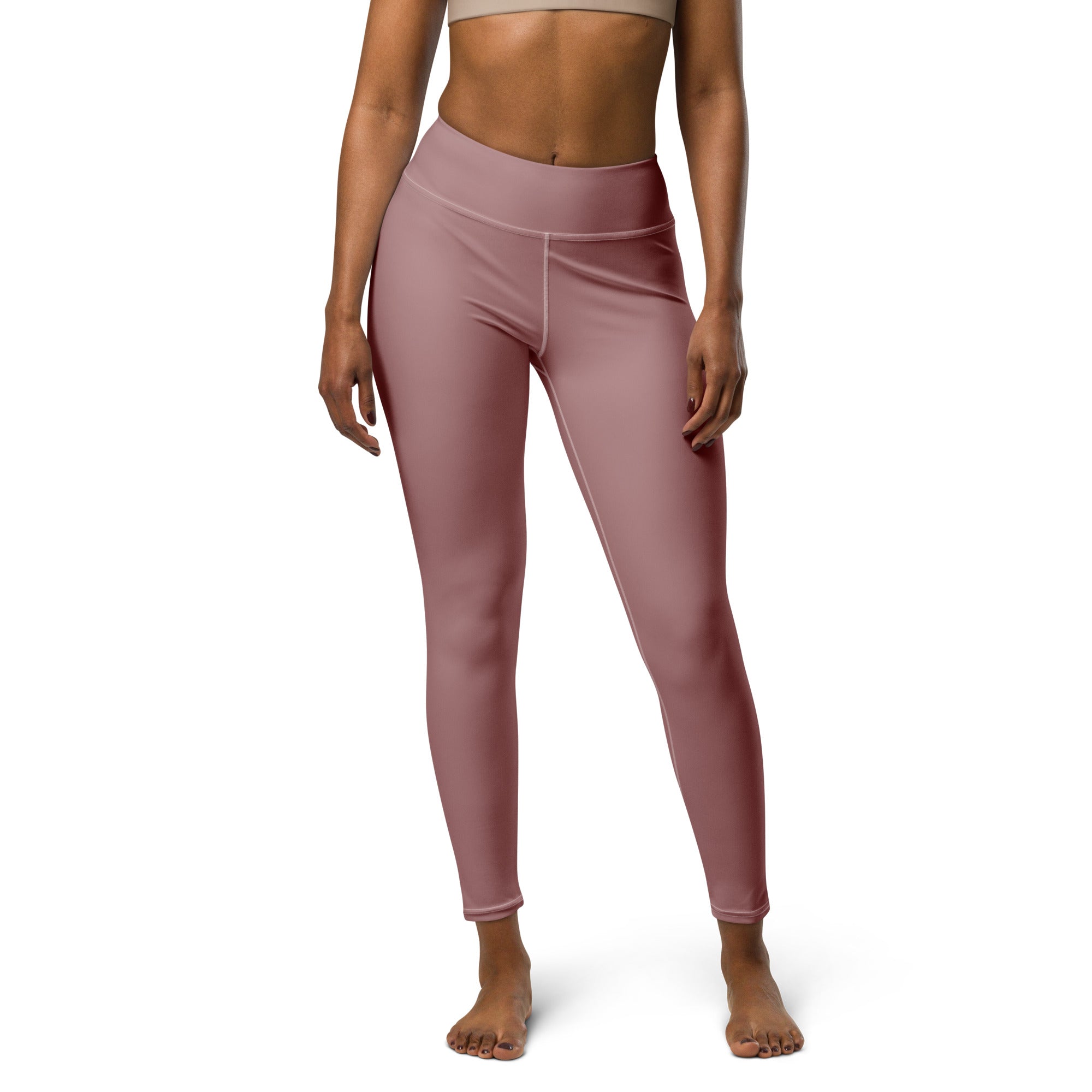 A person standing wearing high-waisted pink yoga leggings and a matching sports bra.