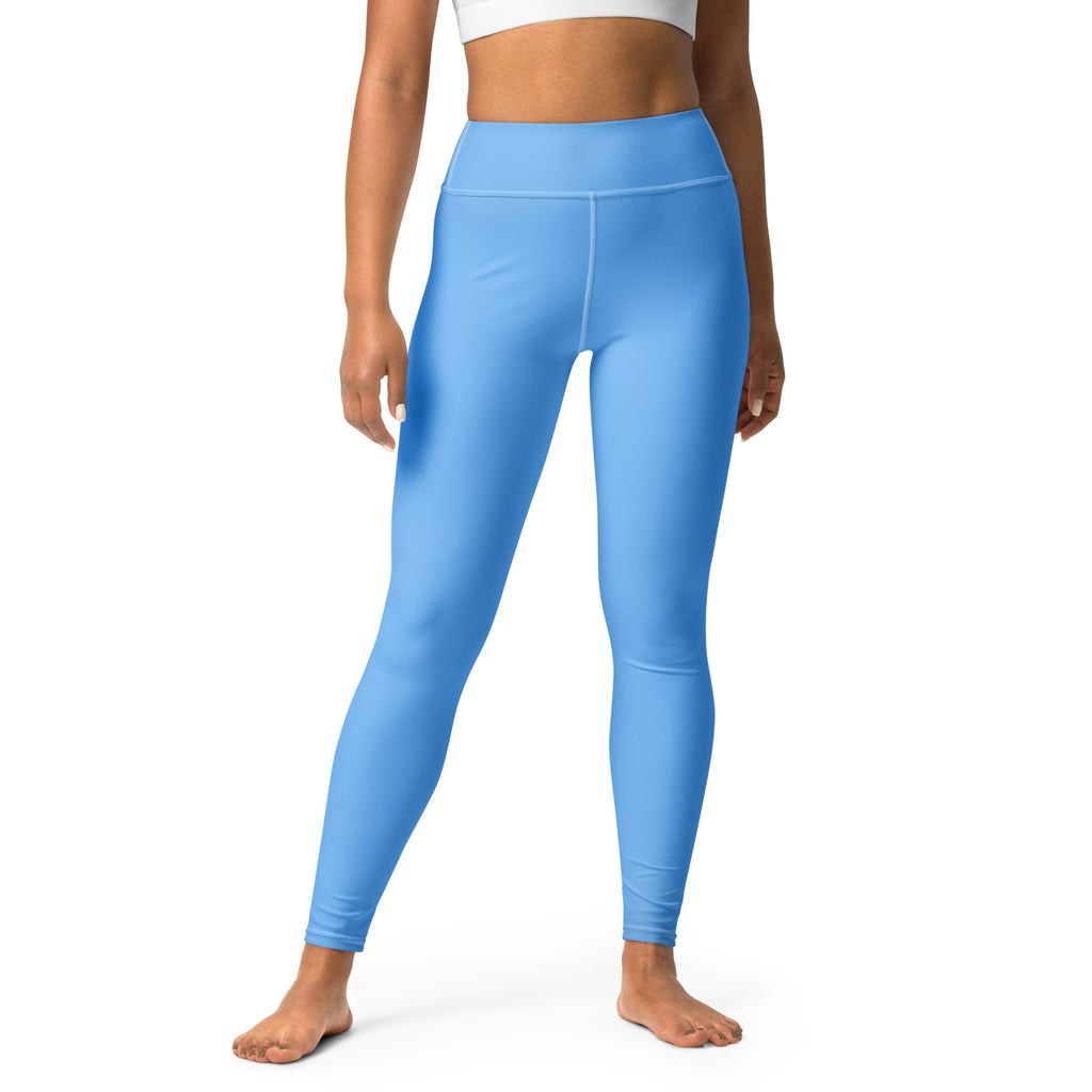 A woman standing wearing blue yoga leggings with a raised waistband and an inside pocket.