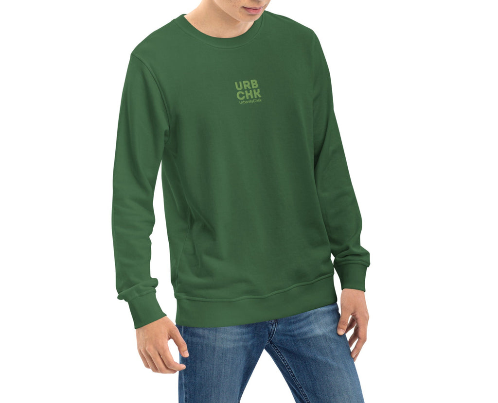 A person wearing a green UrbanityChek crewneck sweatshirt with the brand's logo on the chest.